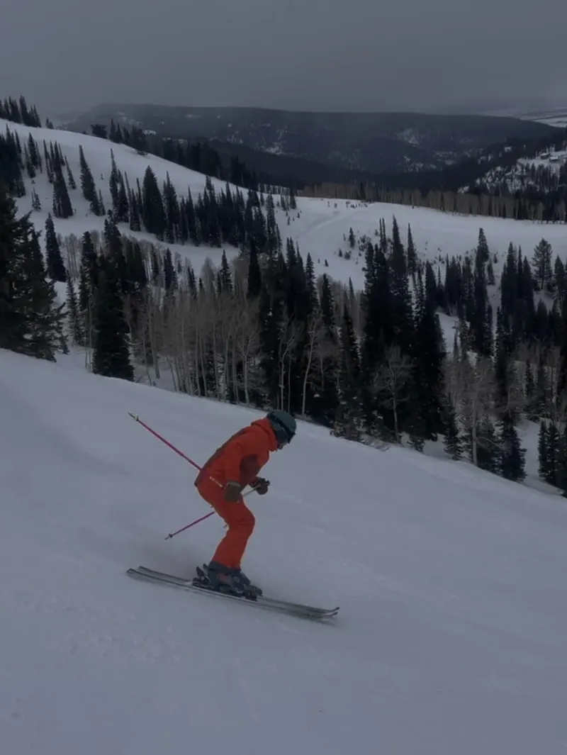 Nick Dawson in a red ski suit carving a turn on a groomed run